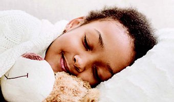 A child sleeping with a teddy bear