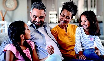 A family sitting on the couch laughing together